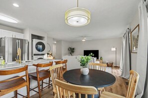 A modern kitchen with a central island, wooden chairs, a round dining table, and a ceiling light fixture. - Game Day Luxury | 2B/2BA Condo By ND | Balcony (South Bend)
