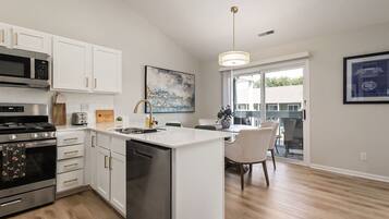 A modern kitchen with stainless steel appliances, white cabinetry, and a large island with a sink.