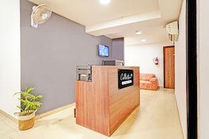 Una reception con un televisore a parete, un estintore e una pianta.