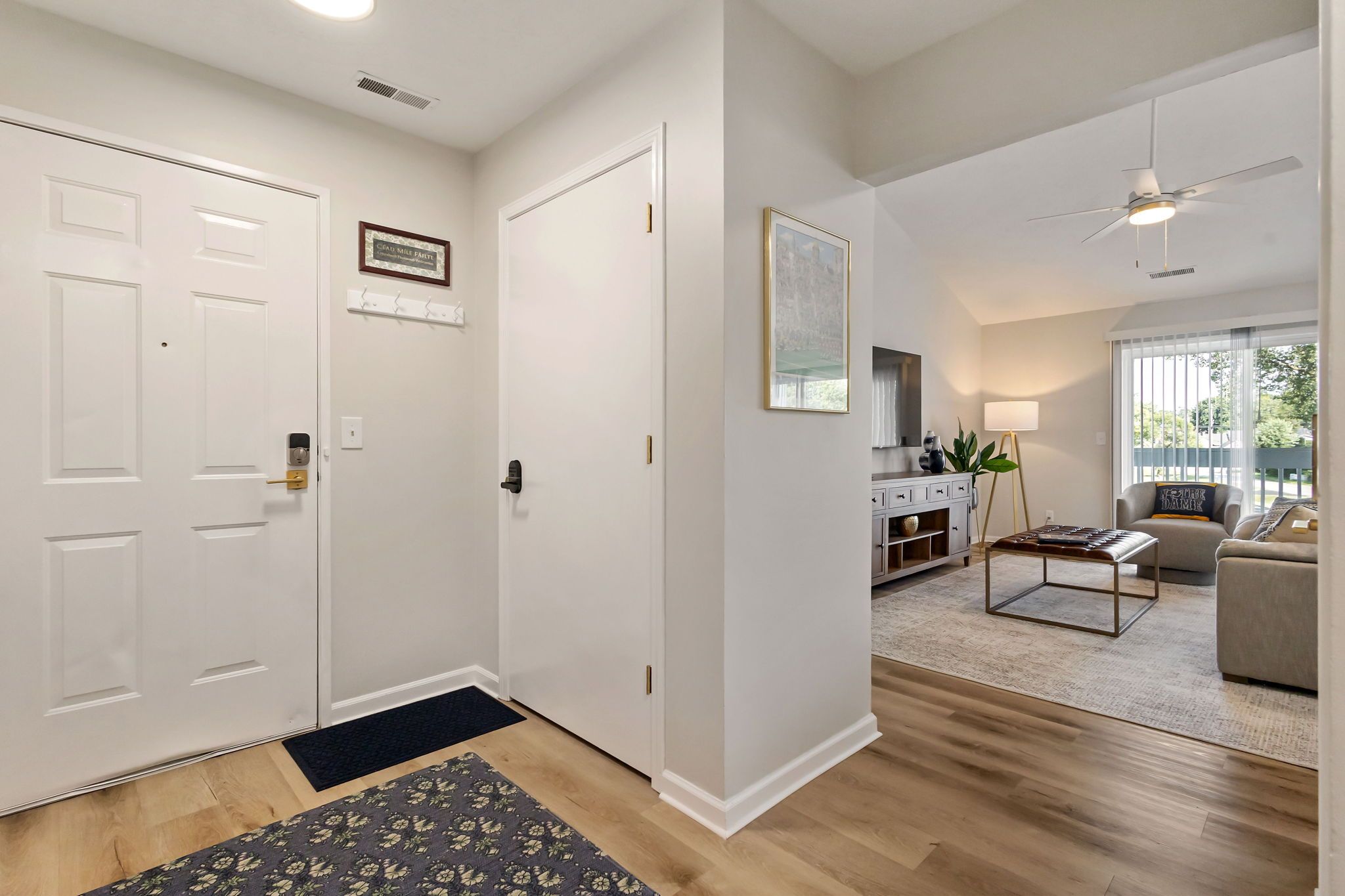 A modern interior with a hallway leading to a living area, featuring a sofa, a coffee table, and a lamp.