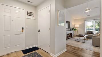 A modern interior with a hallway leading to a living area, featuring a sofa, a coffee table, and a lamp.