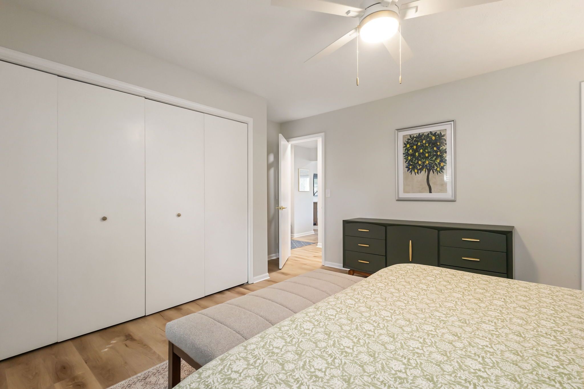 Une chambre à coucher comprenant un lit, une armoire, une commode et un ventilateur de plafond.