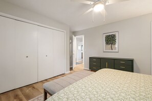 Une chambre à coucher comprenant un lit, une armoire, une commode et un ventilateur de plafond.