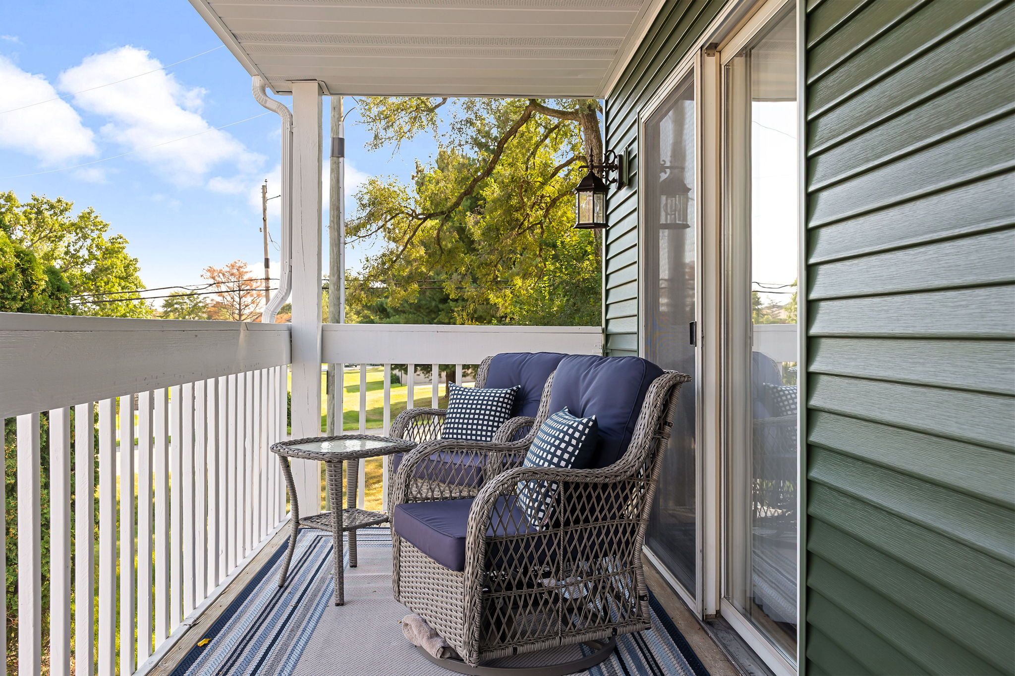 A covered porch with wicker furniture and a small table.