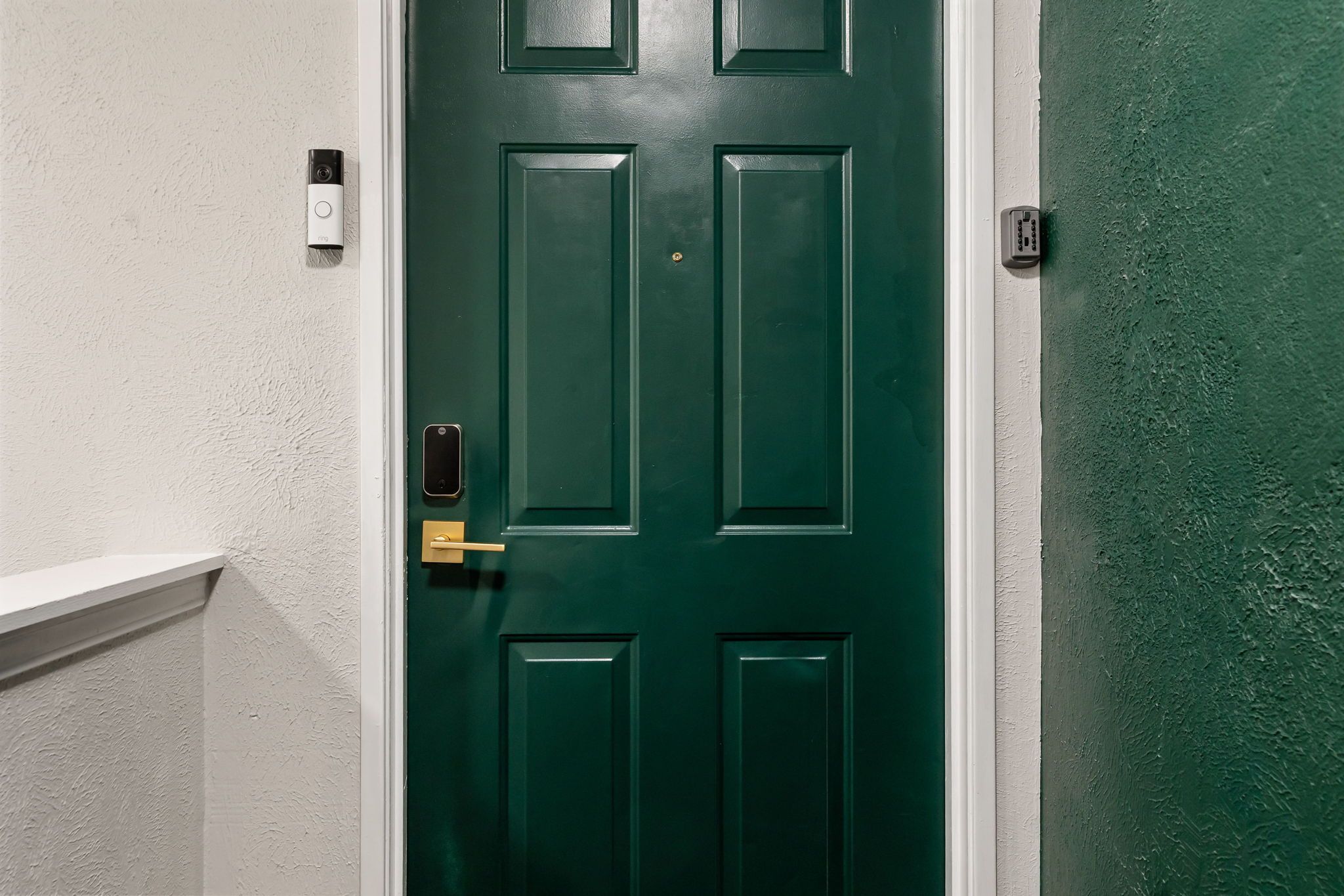 A green door with a keypad lock, a doorbell, and a doorbell camera.