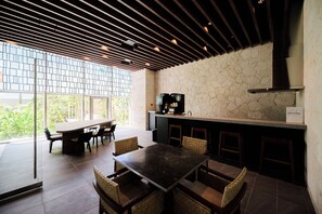 A modern interior with a dining area, a bar, and a view of greenery. - Buranshiera Naha Kainan Puremisuto 905 (Naha)
