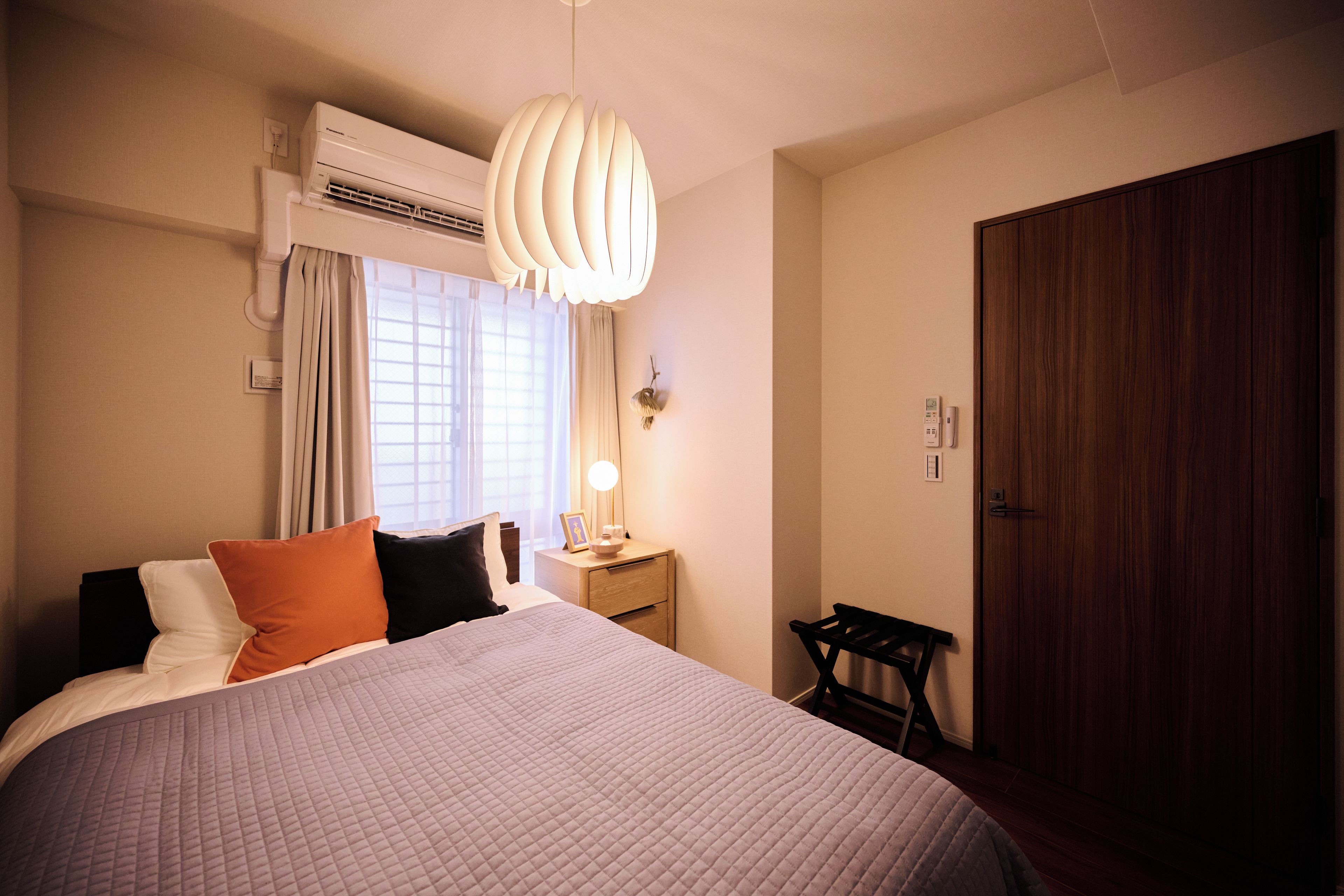 Et hotelværelse med seng, natbord, lampe og et skab.