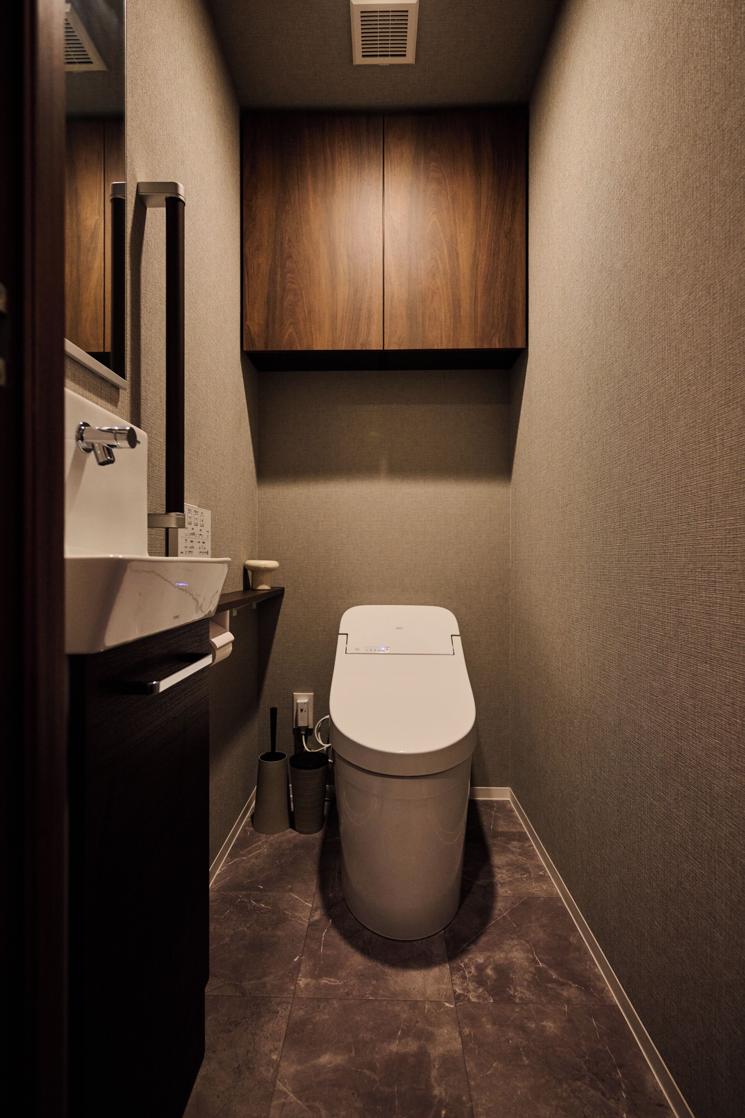 Ein kleines Badezimmer mit modernem Design, ausgestattet mit einem Waschbecken, einer Toilette und einem Schrank.