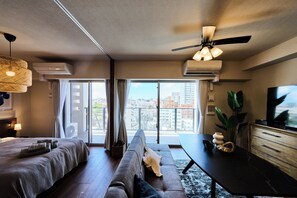 A modern hotel room with a bed, sofa, dining table, and a TV. - Buranshiera Naha Kainan Puremisuto 905 (Naha)