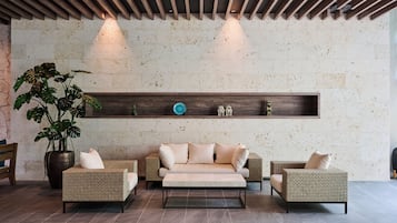 A modern lobby with a sofa set, a potted plant, and a wooden shelf with decorative items.