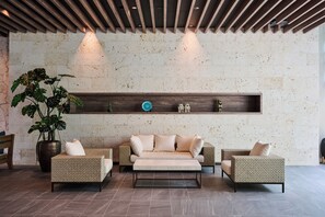 Un vestíbulo moderno con un conjunto de sofás, una planta en maceta y un estante de madera con objetos decorativos.