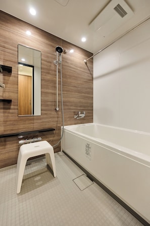 A modern bathroom with a wooden wall, a white bathtub, and a small white stool. - Buranshiera Naha Kainan Puremisuto 905 (Naha)