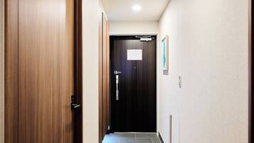 A hallway with wooden flooring, a door with a sign, and a light fixture on the ceiling.