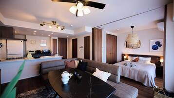 Quarto de hotel moderno com área de refeições, um sofá, uma cama e um ventilador de teto.