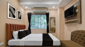 A bedroom with a bed, a TV mounted on the wall, and a window with curtains. - Collection O Park Street Road (Kolkata)