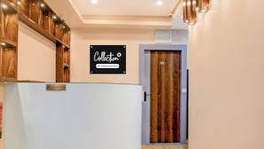 A reception area with a reception desk, a sign indicating 'Collection Company-Serviced', and a wooden door with the number 101. - Collection O Park Street Road (Kolkata)