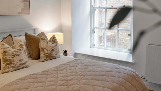 Een slaapkamer met een groot bed, een raam met uitzicht en een lampje op het nachtkastje.