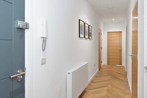 Ein Flur mit einer blauen Tür, einem weißen an der Wand befestigten Telefon und drei gerahmten Bildern.
