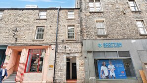 A stone building with a storefront for 'Scottish Building Society' and a visible entrance to a shop named 'Emily's Tailors'.