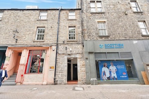 A stone building with a storefront for 'Scottish Building Society' and a visible entrance to a shop named 'Emily's Tailors'. - Modern Apartment in City Centre (Edinburgh)