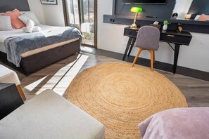 A modern bedroom with a bed, a desk, a chair, and a large woven rug. - Classic Family Room - Sleeps 4 (Greenacre)