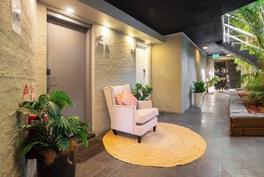 A hallway with a chair, plants, and a textured wall. - Classic Family Room - Sleeps 4 (Greenacre)