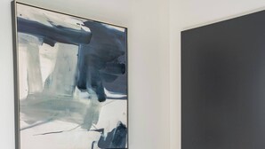 A single bed with white bedding and a blue pillow, a white towel, and a large abstract painting on the wall. - Deluxe Twin Room - Sleeps 3 (Greenacre)