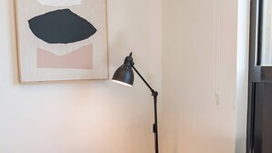 A room with a blue sofa, a black floor lamp, and a painting on the wall. - Deluxe Twin Room - Sleeps 3 (Greenacre)