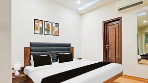 Un dormitorio moderno con una cama grande, una puerta de madera y tres obras de arte enmarcadas en la pared.