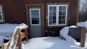 A wooden building with a snow-covered entrance and a bench. - Fox Den French river (Noëlville)