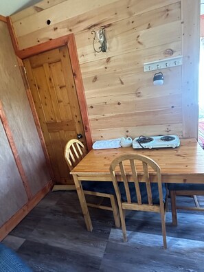 A wooden dining table with chairs, a stove, and a wall-mounted light fixture.