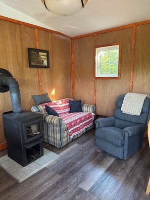 A cozy room with a wood-burning stove, a plaid sofa, and a blue armchair.