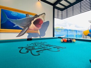 Ein Billardtisch mit einem Hai-Wandbild und einem Schild mit der Aufschrift 'Love of Pool'.