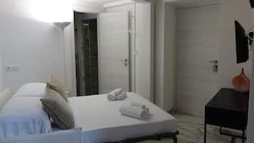 Una habitación de hotel con cama, escritorio, ducha y puerta.