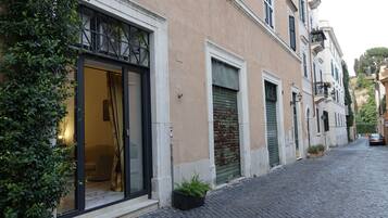 A building with a glass entrance, a closed shutter door, and a cobblestone street.