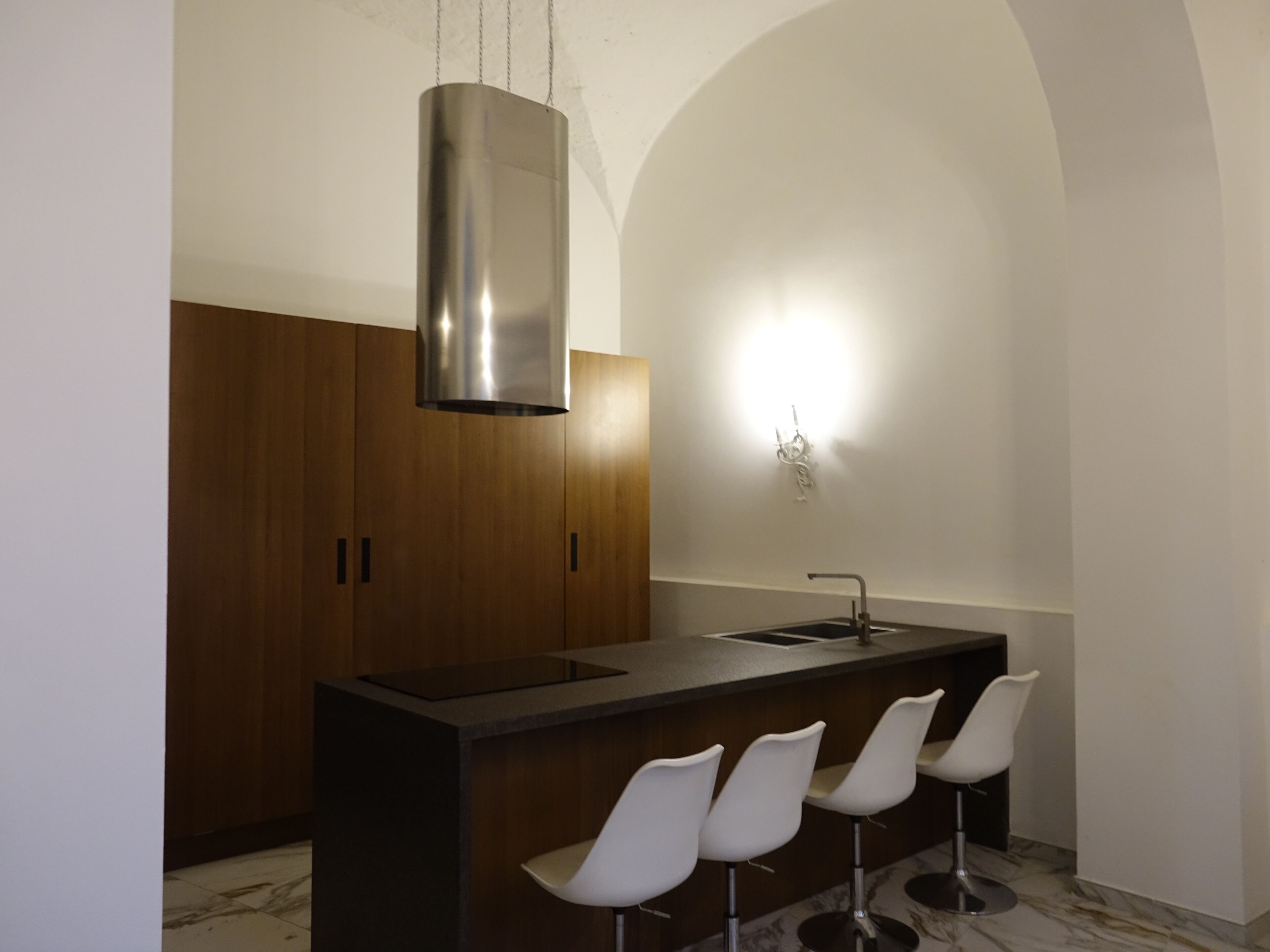 A modern kitchen with a central island, bar stools, and a pendant light.