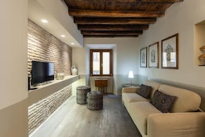 Uma sala de estar com televisão, sofá, lareira e parede de pedra.