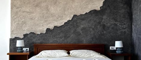 A hotel room with a large bed, two bedside tables with lamps, and a wall with a textured surface.
