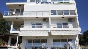 A multi-story building with balconies, a sign reading 'AP RTMEN S Casa Mila,' and a covered outdoor area with furniture. - Casa Mila Apartments - Studio apartment with sea view (Ulcinj)