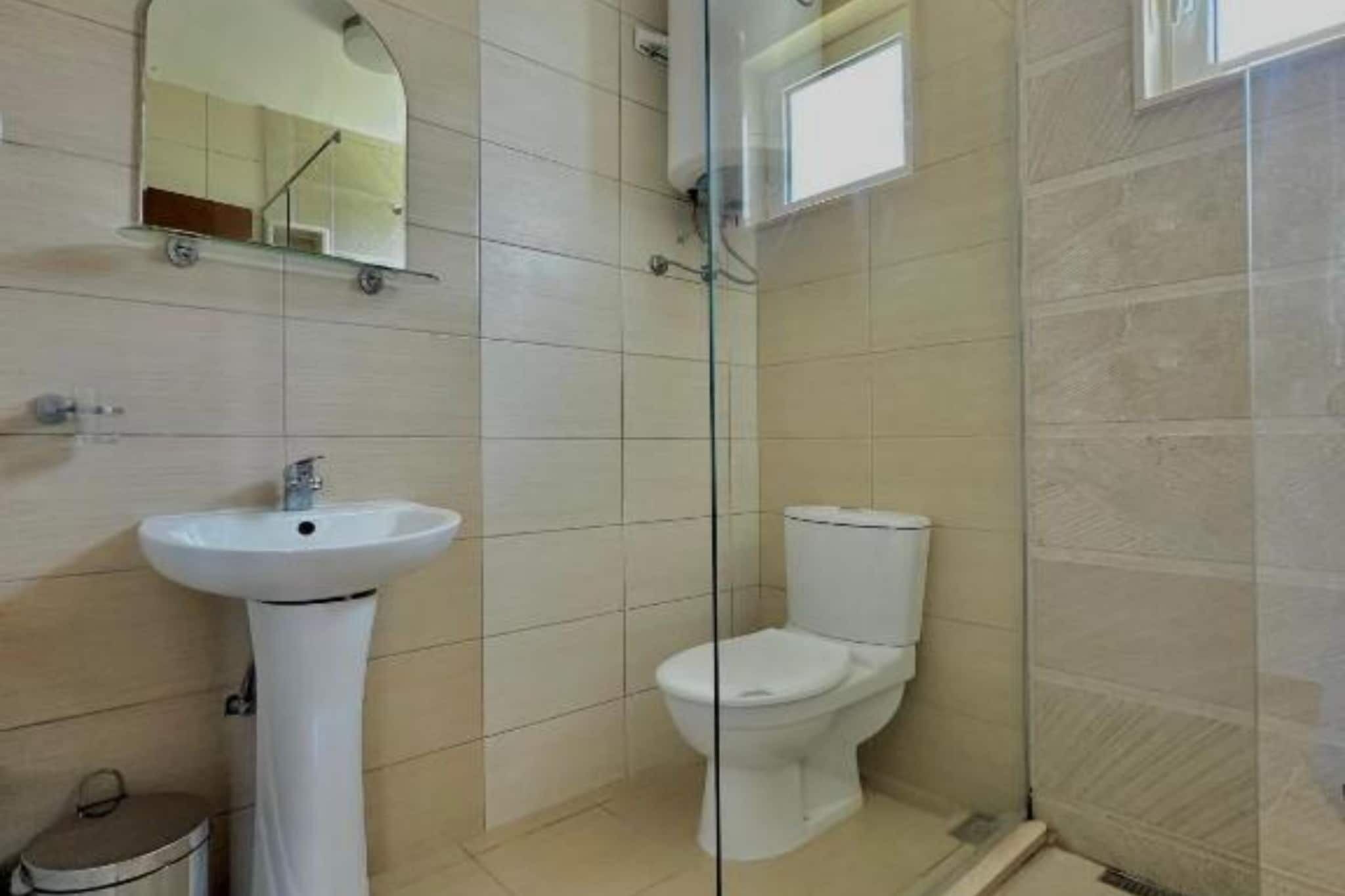 Ein Badezimmer mit einem Standwaschbecken, einer Toilette und einer Duschkabine aus Glas.