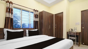 Habitación de hotel con cama, armario y una mesita con tetera y botellas.