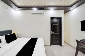 A hotel room with a bed, a door, a wall-mounted air conditioner, and a television. - Super Collection O Nirman Vihar (New Delhi)