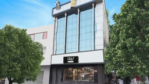 A modern building with a glass facade, a company-serviced sign, and a storefront with a metal gate. - Super Collection O Nirman Vihar (New Delhi)