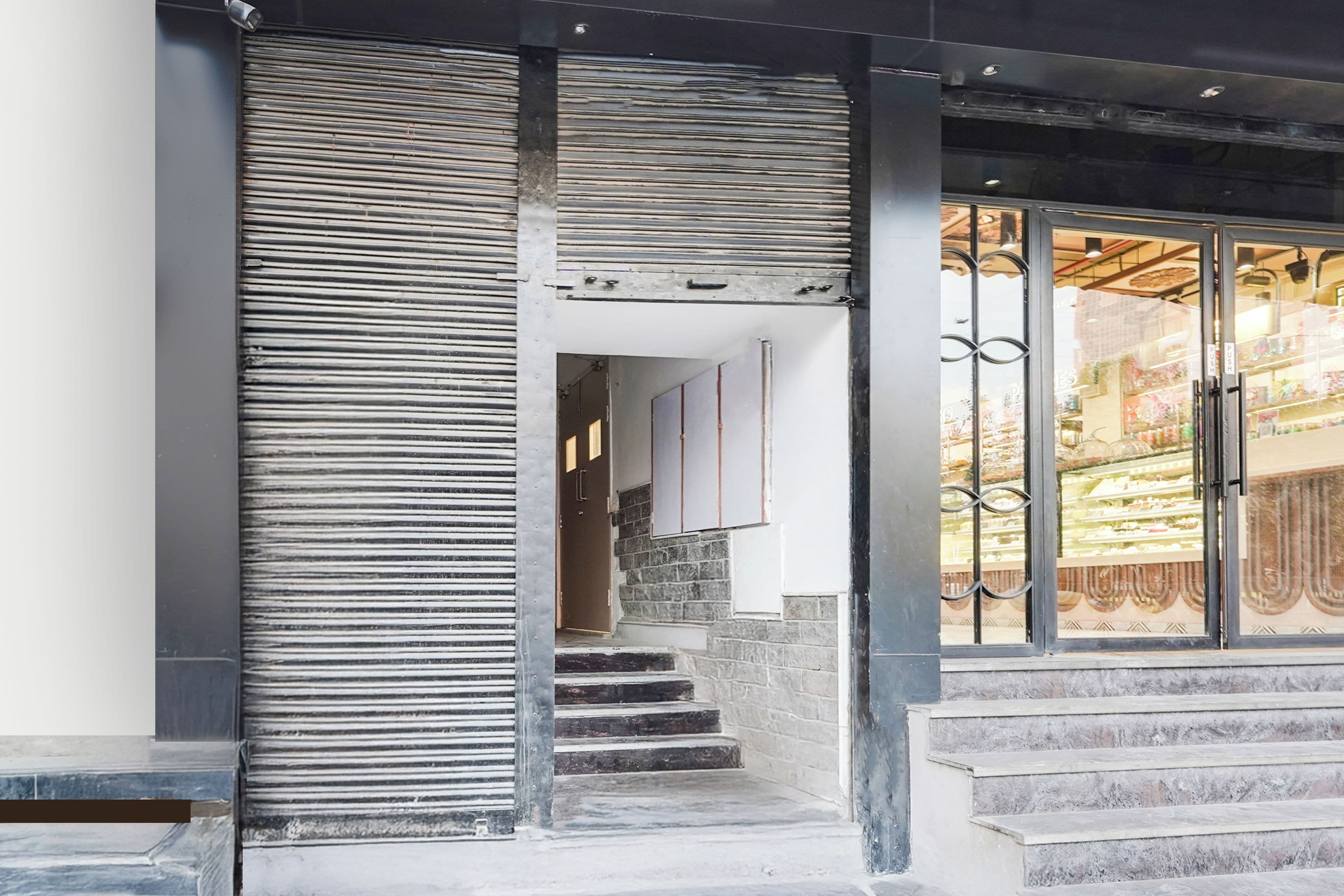 A staircase leading to a building entrance with a metal railing and a glass door with a metal gate.