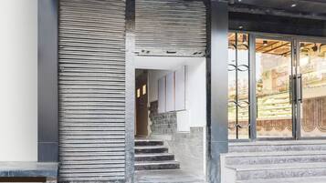 A staircase leading to a building entrance with a metal railing and a glass door with a metal gate.