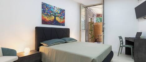 A modern bedroom with a bed, bedside table, and a colorful abstract painting.