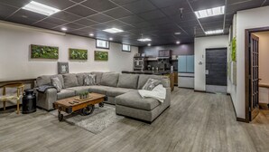 A modern living room with a sectional sofa, a coffee table, and a kitchen area in the background.