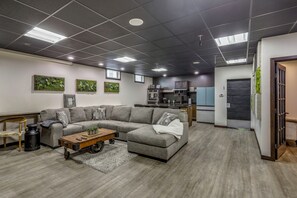 A modern living room with a sectional sofa, a coffee table, and a kitchen area in the background.