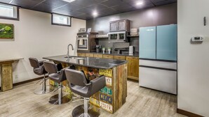 A modern kitchen with a central island, bar stools, a microwave, a refrigerator, and a coffee maker.