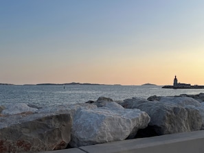 A coastal scene with a lighthouse, calm water, and large rocks in the foreground. - Charming 2-bedroom apartment with parking near port in Sanary-sur-Mer (Sanary-sur-Mer)
